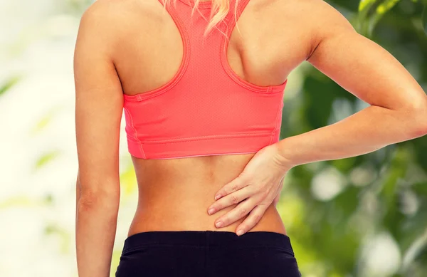 Close up de mulher esportiva tocando suas costas — Fotografia de Stock