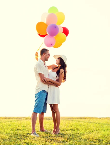 Casal sorridente com balões de ar ao ar livre — Fotografia de Stock