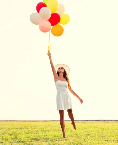 Gülümseyen güneş gözlüğü balonlarla genç kadın — Stok fotoğraf