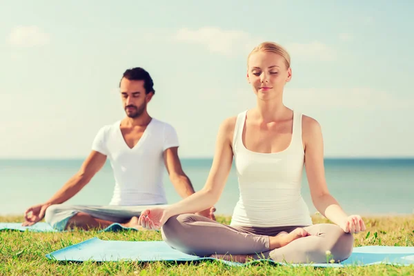 Coppia sorridente fare esercizi di yoga all'aperto — Foto Stock