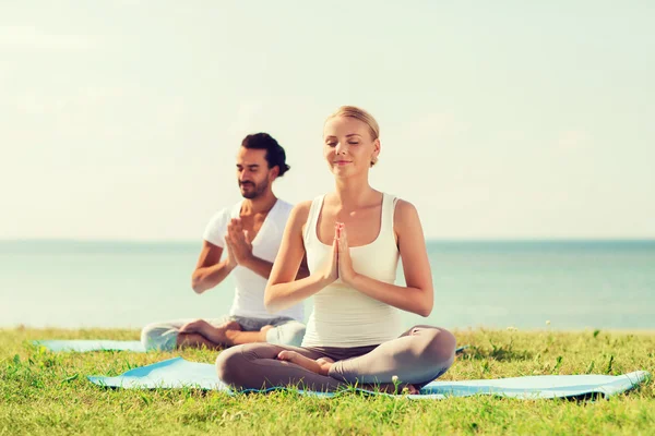 Lächelndes Paar macht Yoga-Übungen im Freien — Stockfoto