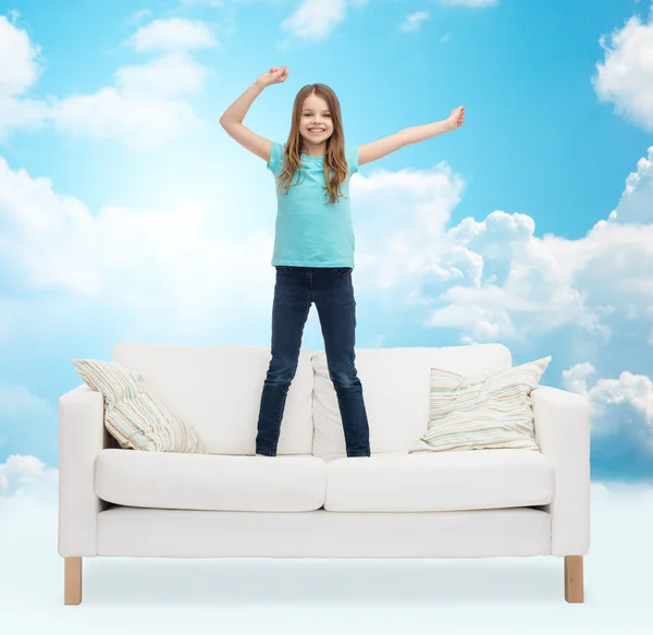 Smiling little girl jumping on sofa — Stock Photo, Image