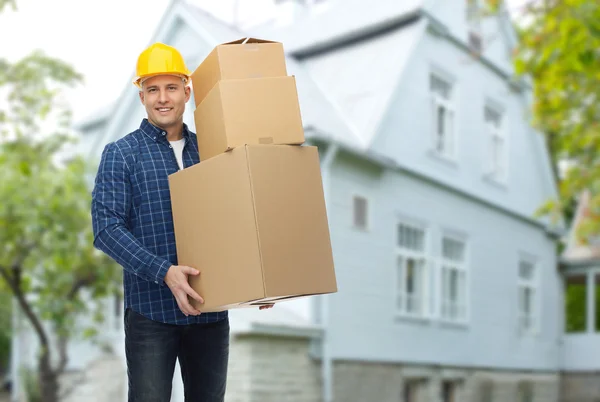 Smiling man in helmet with cardboard boxes — Stock Photo, Image