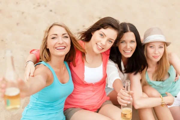Meninas sorridentes com bebidas na praia — Fotografia de Stock