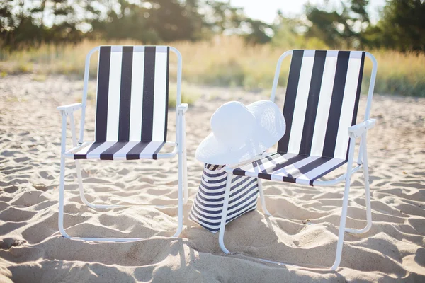 Dos salones de playa con bolsa de playa y sombrero blanco —  Fotos de Stock