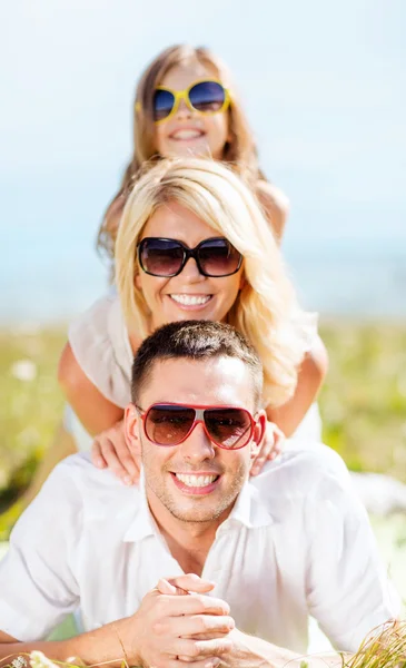 Família feliz com céu azul e grama verde — Fotografia de Stock