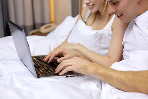 Χαμογελώντας ζευγάρι στο κρεβάτι με φορητό υπολογιστή — Φωτογραφία Αρχείου