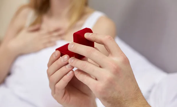 Primer plano de las manos sosteniendo pequeña caja de regalo roja — Foto de Stock