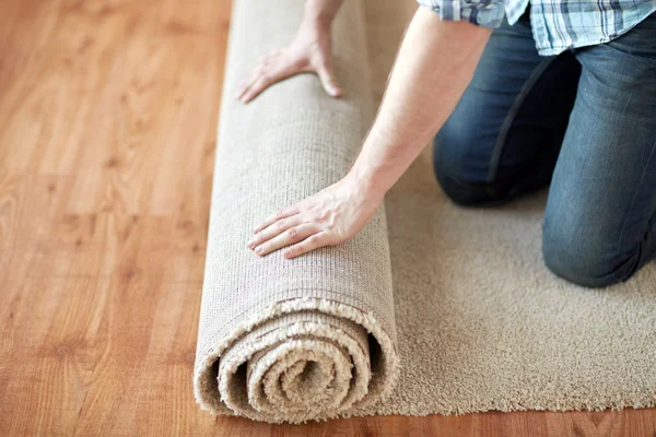 Close up of male hands rolling carpet — Stock Photo, Image