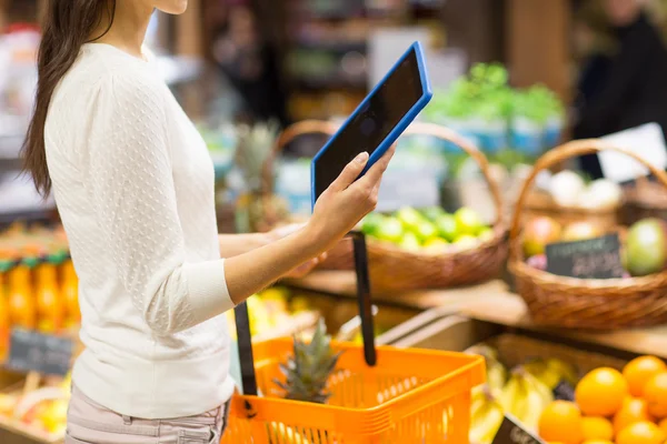 Vrouw met mand en tablet pc in de markt — Stockfoto