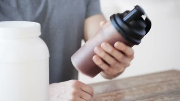 Primer plano del hombre con botella de batido de proteínas y frasco — Vídeos de Stock