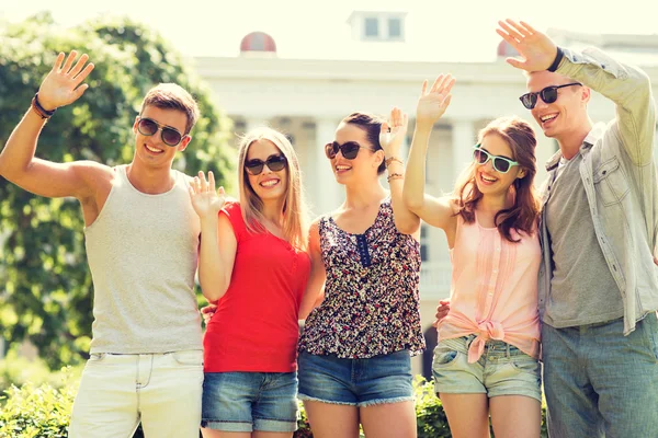 Group of smiling friends waving hands outdoors — Stock Photo, Image