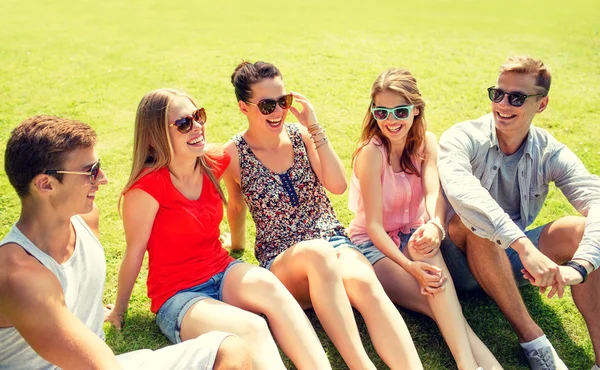 Group of smiling friends outdoors sitting in park — Stock Photo, Image