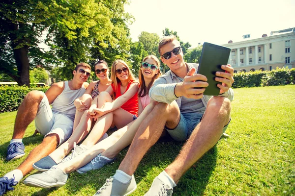 Amigos sonrientes con tablet PC en el parque — Foto de Stock