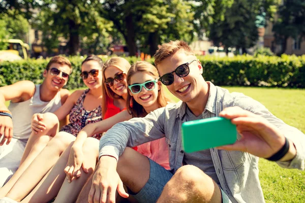 Amigos sonrientes con teléfono inteligente haciendo selfie — Foto de Stock