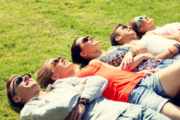 Grupo de amigos sorridentes deitado na grama ao ar livre — Fotografia de Stock