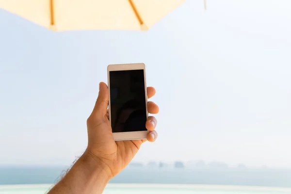 Primer plano de la mano masculina celebración de teléfono inteligente en la playa — Foto de Stock