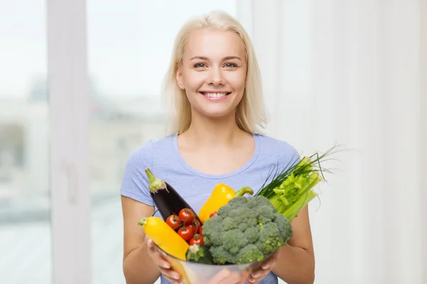 Leende ung kvinna med grönsaker hemma — Stockfoto