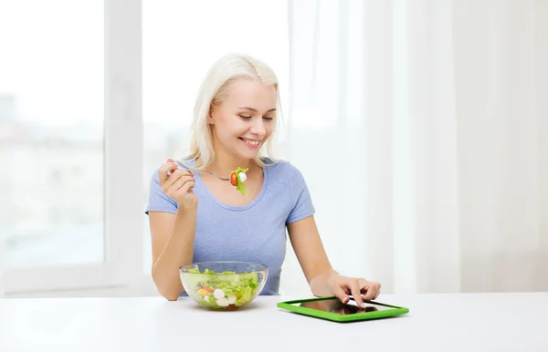 Mulher sorrindo comer salada com tablet pc em casa — Fotografia de Stock