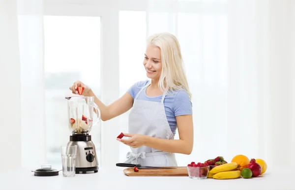 Mulher sorridente com liquidificador preparando shake em casa — Fotografia de Stock