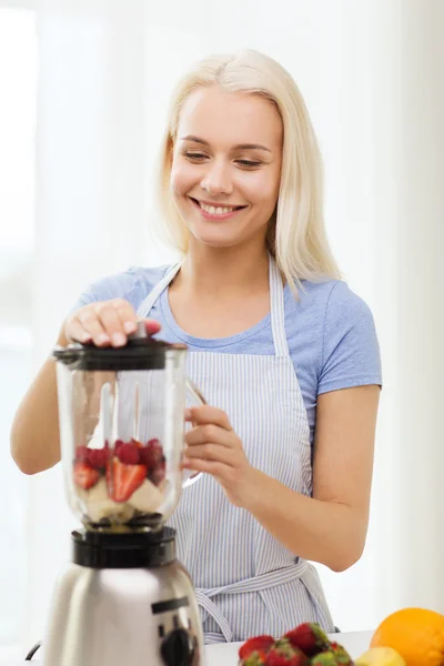 Leende kvinna med blender förbereder skaka hemma — Stockfoto