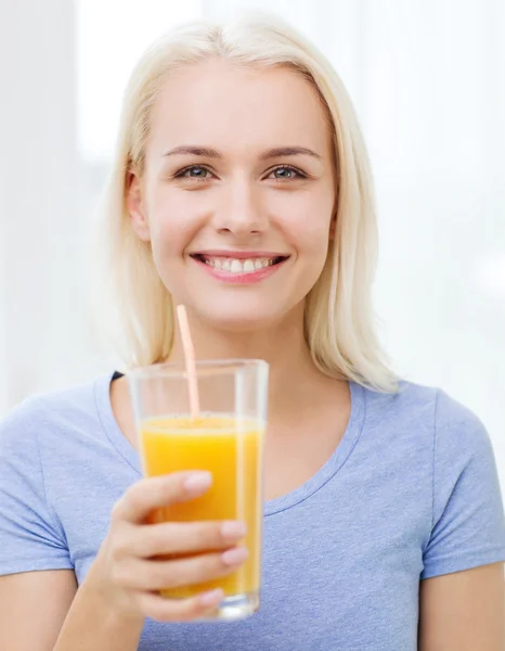 Donna sorridente che beve succo d'arancia a casa — Foto Stock