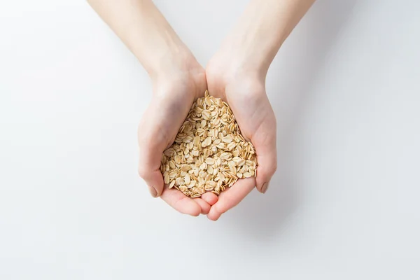 Primer plano de las manos de la mujer sosteniendo copos de avena — Foto de Stock