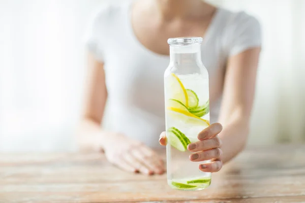 Close up of woman with fruit water in glass bottle — Stock Photo, Image