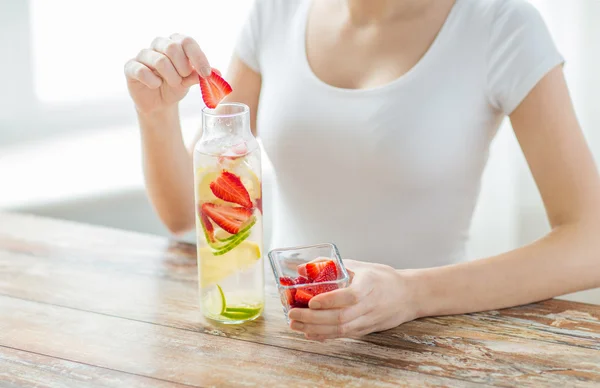 close up of woman with fruit water in glass bottle