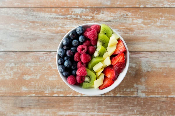 Tutup buah-buahan dan beri dalam mangkuk di atas meja Stok Gambar