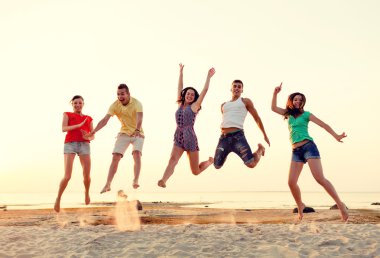 smiling friends dancing and jumping on beach clipart