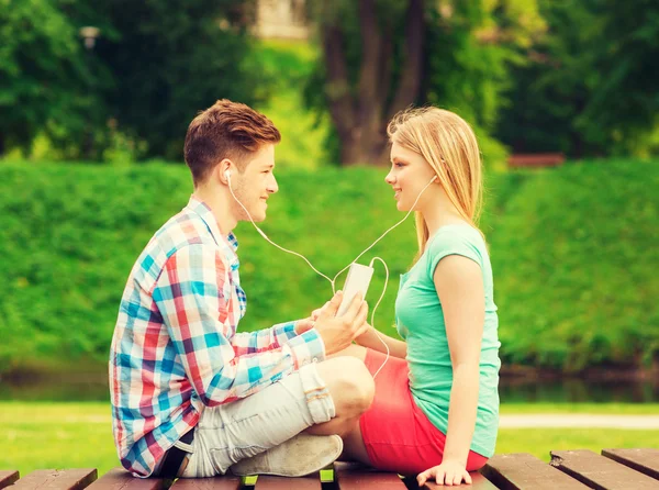 Coppia sorridente con smartphone e auricolari — Foto Stock