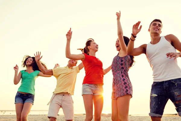 Lachende vrienden dansen op zomer strand — Stockfoto