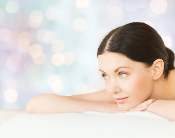 Happy beautiful woman lying on massage desk at spa — Stock Photo, Image