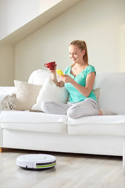 Mujer feliz con teléfono inteligente beber té en casa — Foto de Stock