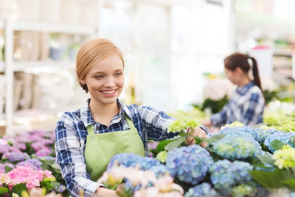 Glückliche Frau kümmert sich um Blumen im Gewächshaus — Stockfoto