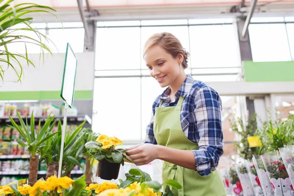 Glad kvinna med blommor i växthus — Stockfoto