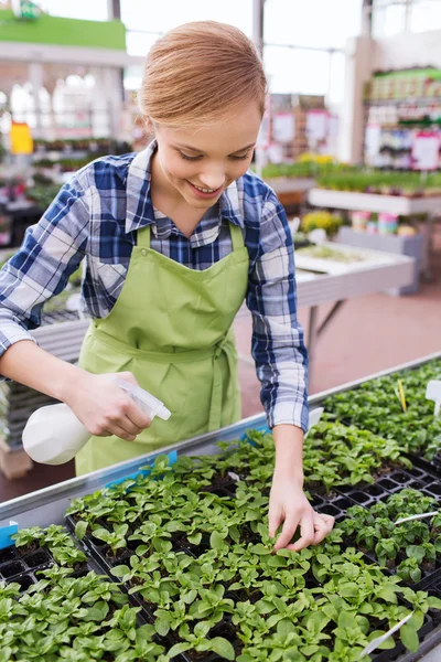 Vrouw met sproeien en zaailing in kas — Stockfoto