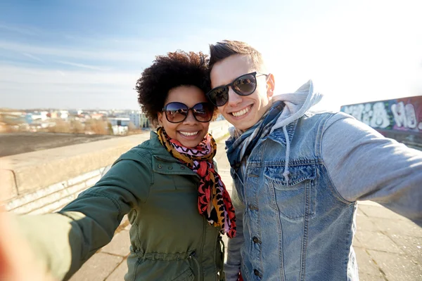 Happy teenage couple taking selfie on city street — Stock Photo, Image