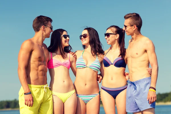 Lächelnde Freunde mit Sonnenbrille am Sommerstrand — Stockfoto