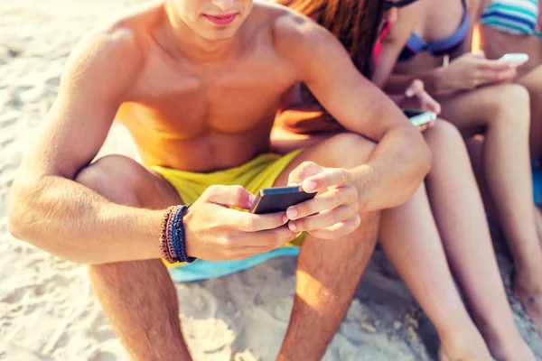 Close up of friends with smartphones on beach — Stock Photo, Image
