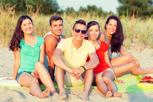 S úsměvem přátelé sedí na pláži v létě — Stock fotografie