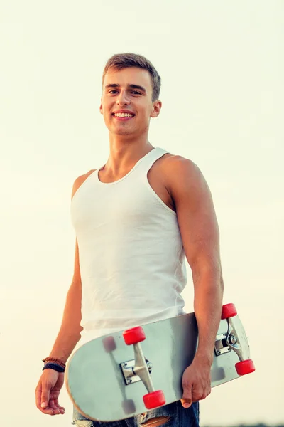 Smiling teenage boy with skateboard outdoors — Stock Photo, Image