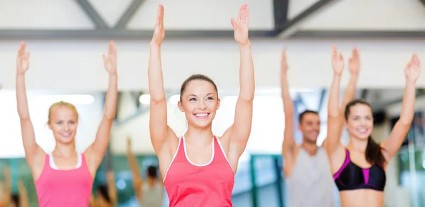 Grupo de personas sonrientes haciendo ejercicio en el gimnasio — Foto de Stock