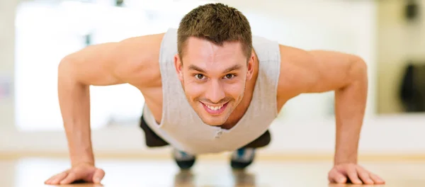 Hombre sonriente haciendo flexiones en el gimnasio —  Fotos de Stock