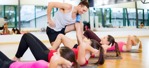 Gruppo di donne sorridenti che fanno sit up in palestra — Foto Stock