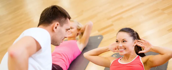 Grupo de mujeres sonrientes haciendo sentadas en el gimnasio —  Fotos de Stock