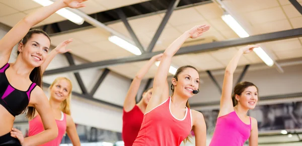 Grupo de personas sonrientes estirándose en el gimnasio — Foto de Stock