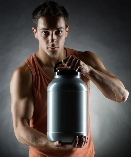 Jovem fisiculturista masculino segurando frasco com proteína — Fotografia de Stock