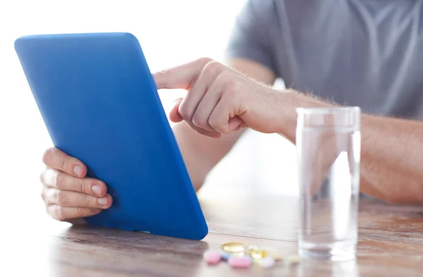 Perto de mãos com tablet pc, comprimidos e água — Fotografia de Stock